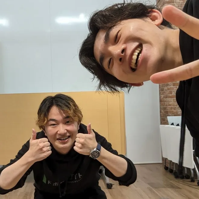 事務所でカメラに向かって笑っている2名の職員。