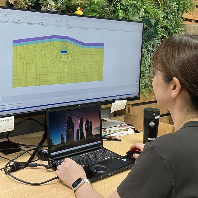 モニタに映した地盤の解析モデルを見ながら作業している職員。